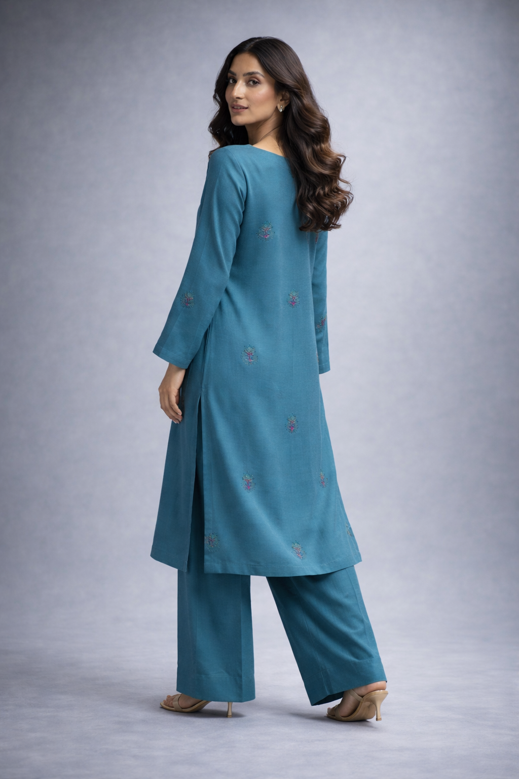 Woman wearing a teal traditional outfit with a plain background