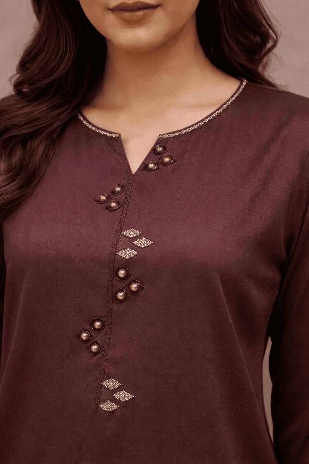 Close-up of a maroon kurta with intricate beadwork on a plain background