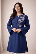 Woman wearing a blue embroidered kurta against a beige background