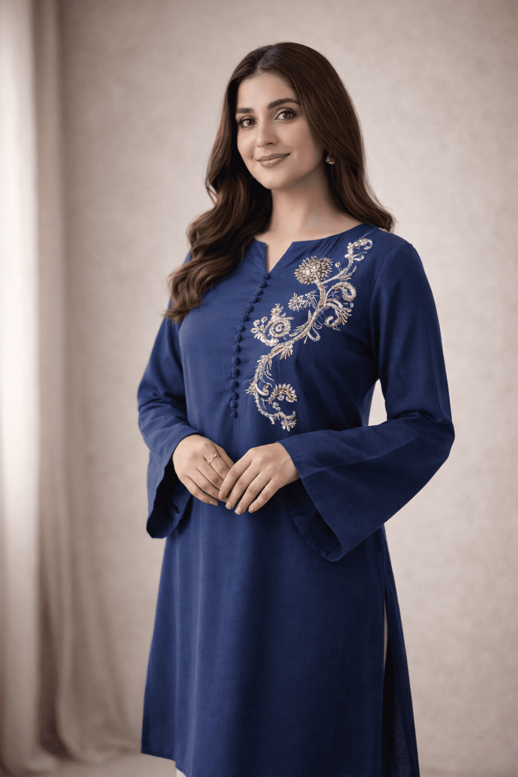 Woman wearing a blue embroidered dress against a beige background